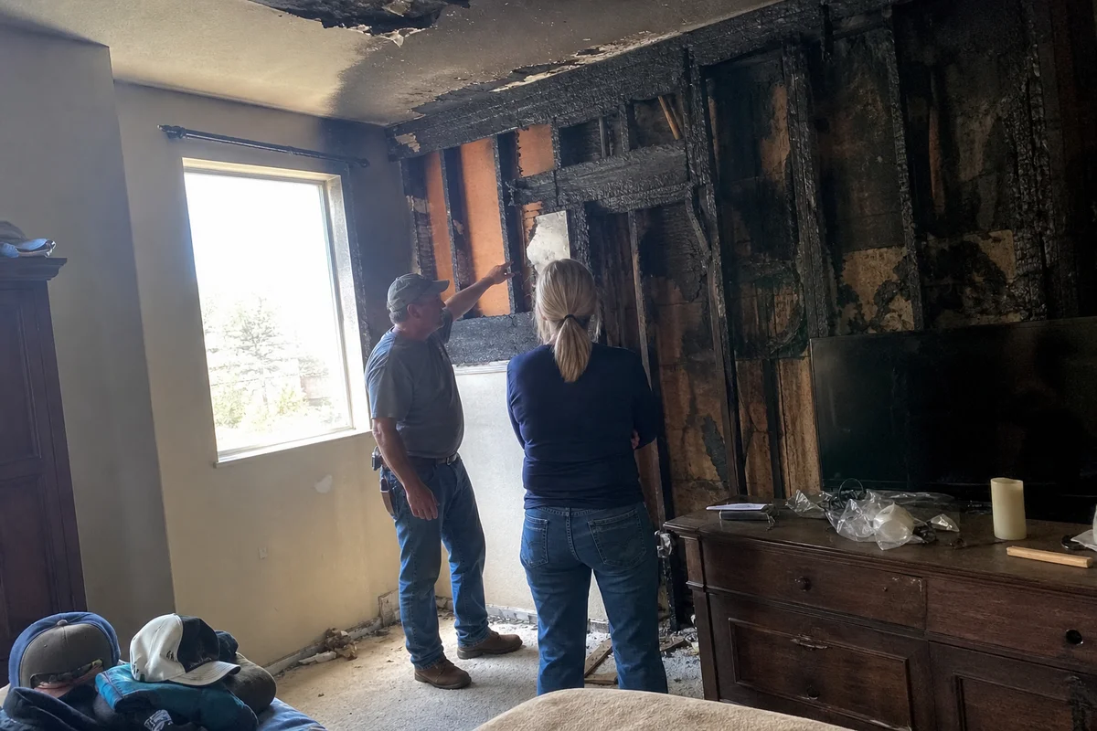 Contractor assessing charred framing with homeowner
